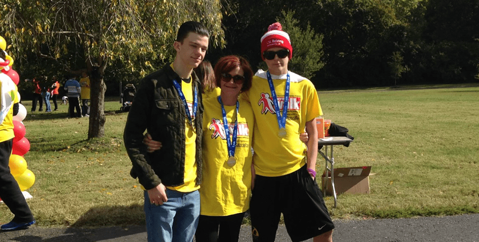 Hemophilia A patient, Rex Herald, with his mom and brother at an event with medals around their necks.