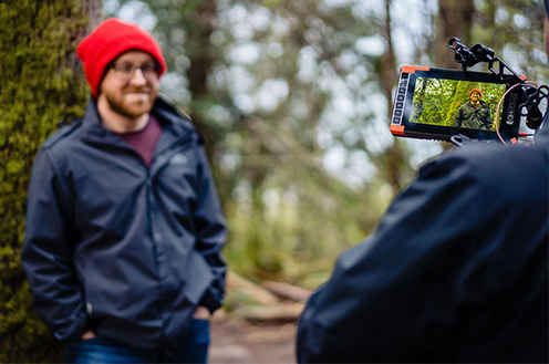 Billy Eshleman, paciente con hemofilia A, usando un gorro rojo y sonriendo mientras es entrevistado en el bosque