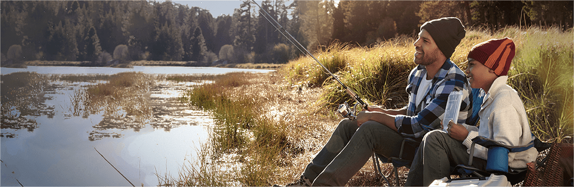Father and son sitting near a pond A father and son sitting near a pond holding a fishing rod